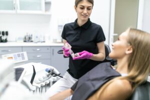 Closeup of dentist's hands explaining teeth model to female patient at clinic