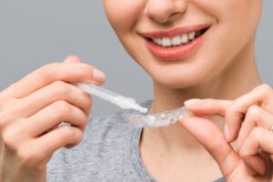 A young woman does a home teeth whitening procedure. Whitening tray with gel.