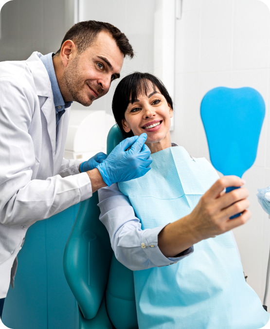 Dentist and patient smiling as the patient examines her teeth in a hand mirror during a dental checkup.