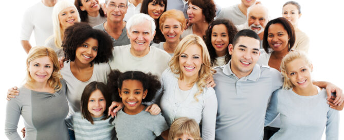 A diverse group of people of various ages and ethnicities, smiling and standing close together against a white background.