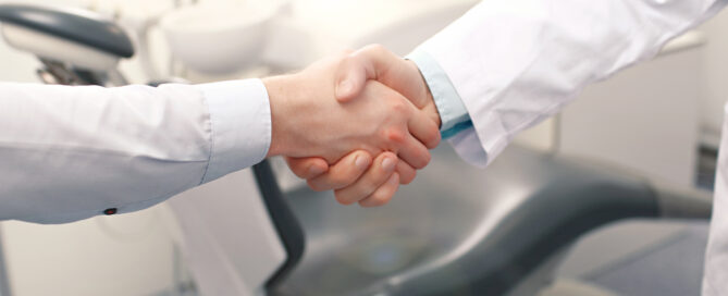 A dentist and a patient are handshaking