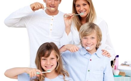 A family of four brushing their teeth together, standing in front of a bathroom counter with toiletries.