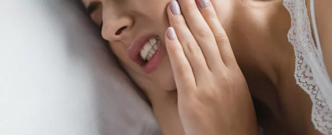 close-up view of young woman suffering from bruxism while lying in bed