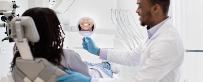 Dentist showing a patient their smile in a hand mirror during a dental appointment in a modern clinic.